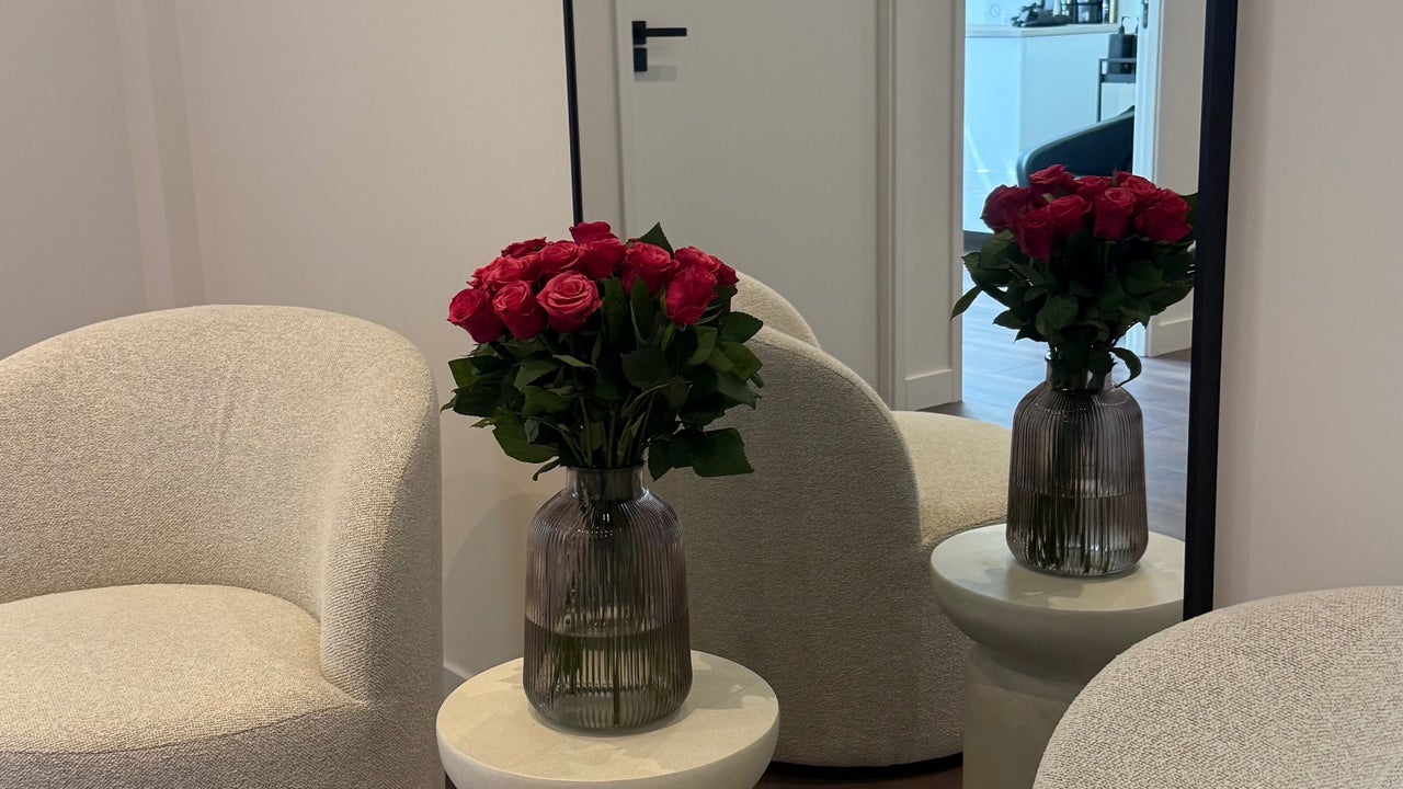 Rode rozen in een vaas op een bijzettafel tussen de boucléstoelen
