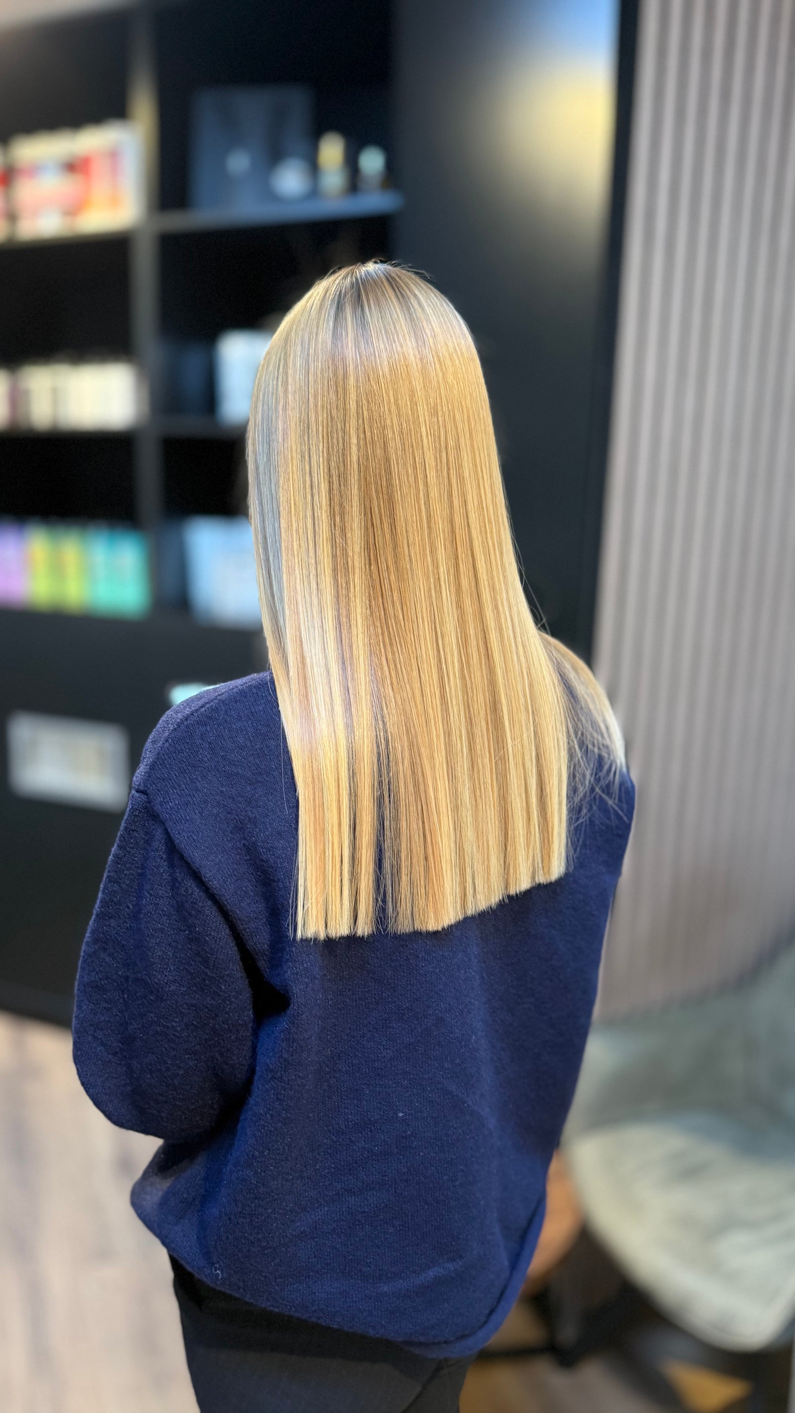 Lang blond haar, steil en glanzend, van achteren gezien in de salon